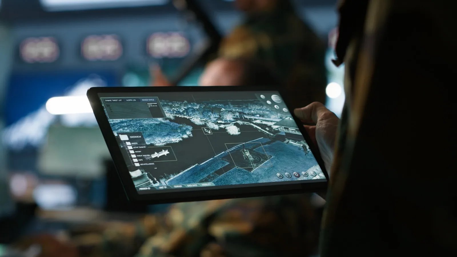 A soldier holding a rugged tablet showing a tactical situation map
